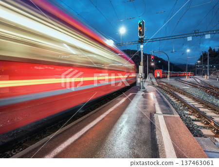 Blurred red passenger train passing mountain railway station Blurred red passenger train passing mountain railway station 137463061