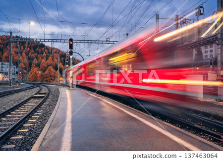 Blurred red passenger train passing mountain railway station 137463064