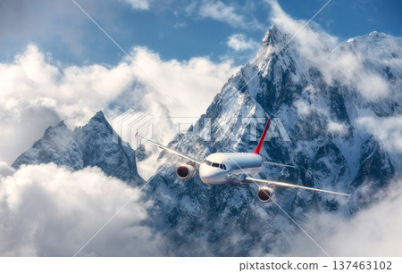 Commercial airplane flying over snow-covered mountains in clouds Commercial airplane flying over snow-covered mountains in clouds 137463102