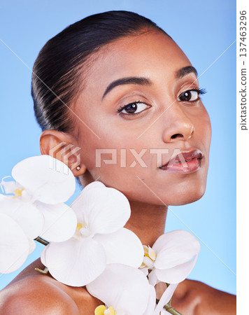 Flower, skincare and portrait of woman in studio for beauty, wellness and organic body care on blue background. Floral, face and Indian female model with petals for eco friendly dermatology or shine Flower, skincare and portrait of woman in studio for beauty, wellness and organic body care on blue background. Floral, face and Indian female model with petals for eco friendly dermatology or shine 137463296