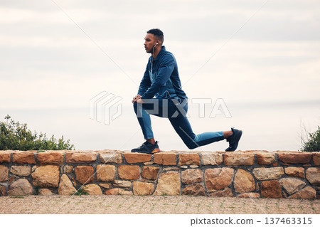 Man, lunge and stretching on rocks, outdoor earphones or for thinking, music for fitness, health or wellness. Runner guy, warm up and training for marathon with streaming, vision or workout in nature 137463315