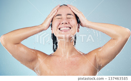 Happy woman, shower and water drops in hygiene, washing or grooming against a blue studio background. Female person smile in relax body wash, cleaning or skincare routine under rain in bathroom Happy woman, shower and water drops in hygiene, washing or grooming against a blue studio background. Female person smile in relax body wash, cleaning or skincare routine under rain in bathroom 137463585