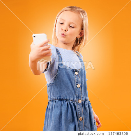 Kiss, selfie or child in studio with confidence or mockup space for photograph memory on web. Fashion, orange background or young girl taking pictures online on a social media app to post on internet 137463806