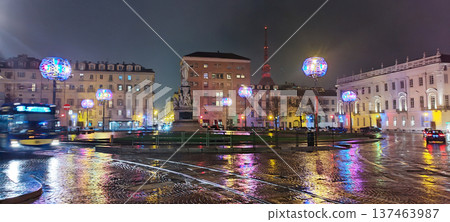 Piazza carlo alberto in turin, italy, showing the monument, historic buildings, glowing decorative lights, and blurred vehicles creating vibrant reflections on the wet street on a winter night 137463987