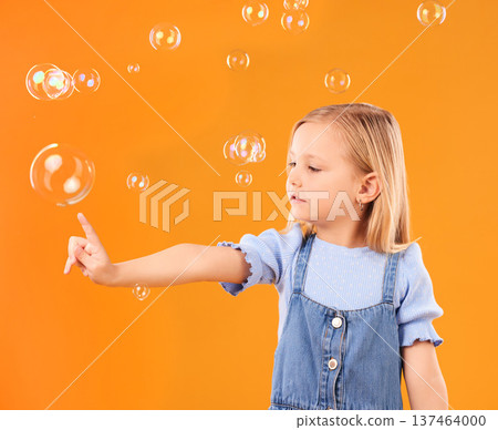 Young girl child, pop bubbles and game, playing and fun with youth isolated on orange background. Liquid soap, development with kid from Australia in studio, playful and toys with childhood Young girl child, pop bubbles and game, playing and fun with youth isolated on orange background. Liquid soap, development with kid from Australia in studio, playful and toys with childhood 137464000