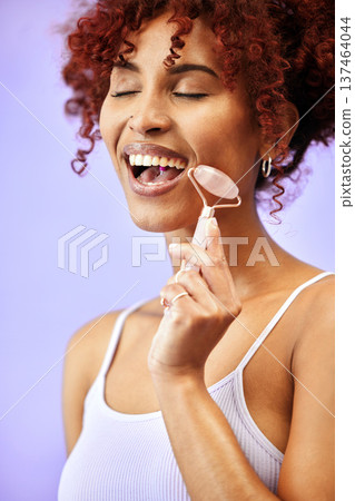 Skincare, rose quartz and woman in studio for wellness, anti aging or collagen circulation on purple background. Crystal, beauty and lady model with jade roller facial, massage or lymphatic drainage Skincare, rose quartz and woman in studio for wellness, anti aging or collagen circulation on purple background. Crystal, beauty and lady model with jade roller facial, massage or lymphatic drainage 137464044