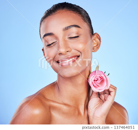 Rose, flower and skincare of woman in studio for eco cosmetics, natural glow and aesthetic on blue background. Face, happy indian model and beauty and floral plants, sustainability and dermatology Rose, flower and skincare of woman in studio for eco cosmetics, natural glow and aesthetic on blue background. Face, happy indian model and beauty and floral plants, sustainability and dermatology 137464051