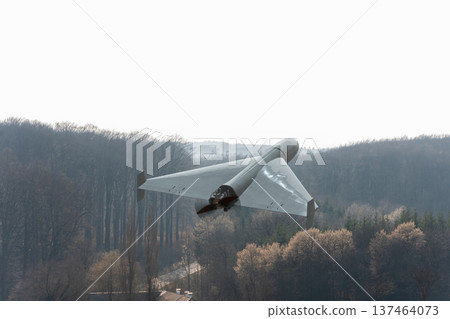 Military drone flying above forest and distant hills 137464073
