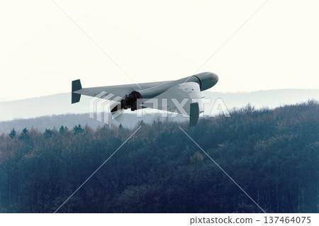 Kamikaze attack drone flies above forest and hilly natural landscape. Kamikaze attack drone flies above forest and hilly natural landscape. 137464075