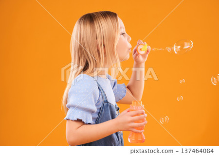 Girl, child and blowing bubbles in studio for fun, games and childhood development on mockup orange background. Profile of kid playing with soap bubble wand, toys and breathing activity for freedom Girl, child and blowing bubbles in studio for fun, games and childhood development on mockup orange background. Profile of kid playing with soap bubble wand, toys and breathing activity for freedom 137464084