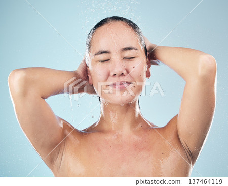 Skincare, shower and woman cleaning hair in studio isolated on a blue background. Water splash, hygiene and model washing, cosmetic and bathing in wellness, healthy skin or beauty of body in bathroom Skincare, shower and woman cleaning hair in studio isolated on a blue background. Water splash, hygiene and model washing, cosmetic and bathing in wellness, healthy skin or beauty of body in bathroom 137464119