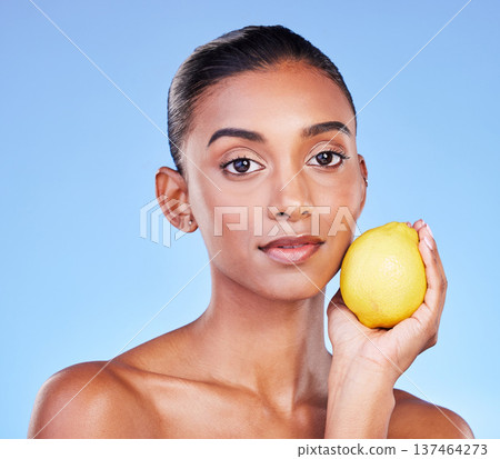 Lemon, portrait or natural skincare of woman in studio for vitamin c benefits, eco cosmetics or nutrition. Face of indian model, healthy beauty or citrus fruit of vegan dermatology on blue background Lemon, portrait or natural skincare of woman in studio for vitamin c benefits, eco cosmetics or nutrition. Face of indian model, healthy beauty or citrus fruit of vegan dermatology on blue background 137464273