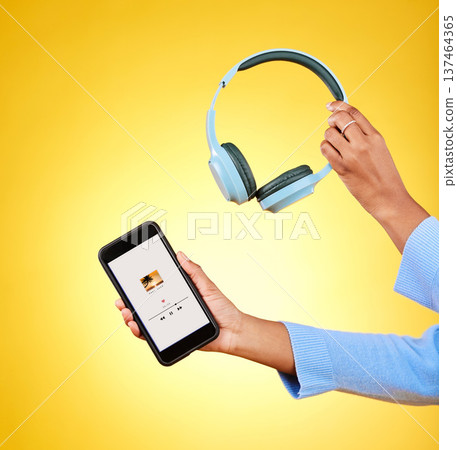 Music, hands and phone and headphones on app for a streaming service. Audio, technology and person with a mobile app for the radio or listening to a podcast online for UI screen on yellow background Music, hands and phone and headphones on app for a streaming service. Audio, technology and person with a mobile app for the radio or listening to a podcast online for UI screen on yellow background 137464365