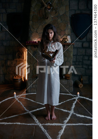 Lady in white practices ancient magical exorcism invocation surrounded by relics reciting a spell 137464380