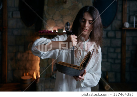 Woman in sacred chamber performs ancient ritual with herbs and candlelight Woman in sacred chamber performs ancient ritual with herbs and candlelight 137464385
