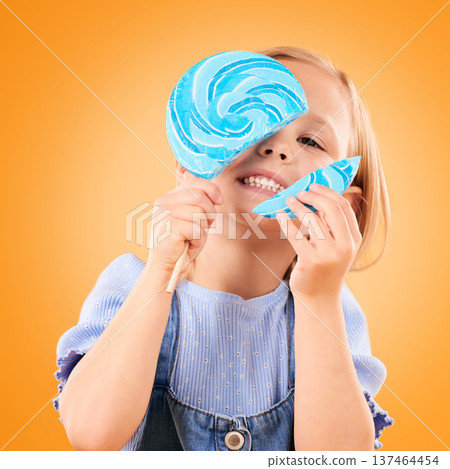 Broken lollipop, candy and a child in studio for sweets, color spiral or sugar for energy. Portrait of happy girl kid on orange background excited about eating snack, dessert or unhealthy food Broken lollipop, candy and a child in studio for sweets, color spiral or sugar for energy. Portrait of happy girl kid on orange background excited about eating snack, dessert or unhealthy food 137464454