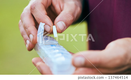 Pills, medicine box and hand closeup of a sport athlete on a soccer field with tablet and drugs for health. Supplements, container and outdoor with a man holding wellness and medication inventory Pills, medicine box and hand closeup of a sport athlete on a soccer field with tablet and drugs for health. Supplements, container and outdoor with a man holding wellness and medication inventory 137464514