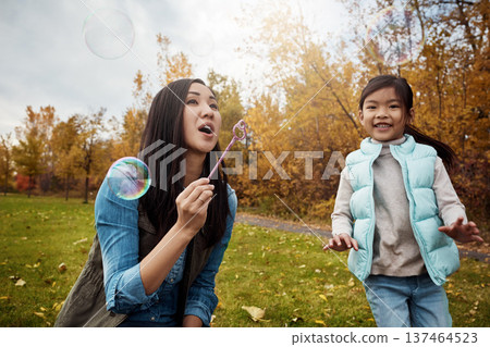 Asian, child and mother blowing with bubbles in park for playful childhood or outdoor bonding. Mom, kid or daughter with wand for parenting, development or fun magical moments together in nature Asian, child and mother blowing with bubbles in park for playful childhood or outdoor bonding. Mom, kid or daughter with wand for parenting, development or fun magical moments together in nature 137464523