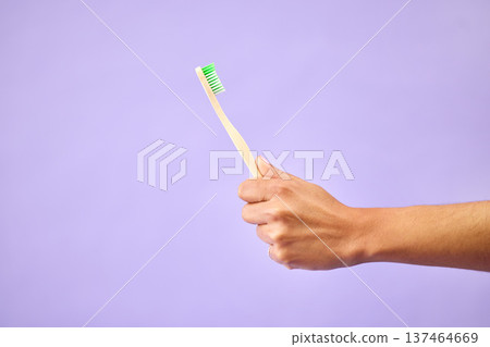 Dental, teeth whitening and hand with toothbrush in studio for oral care, wellness and hygiene on purple background. Mouth, cleaning and person show bamboo tool for fresh breath, tooth or gum health 137464669