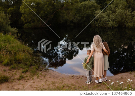 Gentle Mother Guards Kids Outside. Mother Tenderly Protects Children By Peaceful Waters Gentle Mother Guards Kids Outside. Mother Tenderly Protects Children By Peaceful Waters 137464960