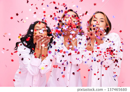 Blow, friends and women in studio with confetti for clothing promotion, fashion sale and discount. Excited, diversity and female people on pink background for bonding, celebration and having fun 137465680