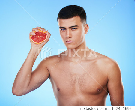 Squeeze, grapefruit and skincare with portrait of man in studio for health, detox and natural cosmetics. Vitamin c, nutrition and spa with person and fruit on blue background for self care and glow Squeeze, grapefruit and skincare with portrait of man in studio for health, detox and natural cosmetics. Vitamin c, nutrition and spa with person and fruit on blue background for self care and glow 137465695