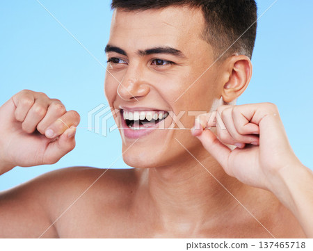 Happy man, face and dental floss in teeth cleaning, hygiene or grooming against a blue studio background. Male person or model smile with flossing in oral, tooth whitening or gum and mouth care 137465718
