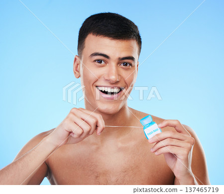 Happy man, portrait and dental floss for teeth cleaning, hygiene or grooming against a blue studio background. Male person or model smile with flossing in oral, tooth whitening or gum and mouth care Happy man, portrait and dental floss for teeth cleaning, hygiene or grooming against a blue studio background. Male person or model smile with flossing in oral, tooth whitening or gum and mouth care 137465719