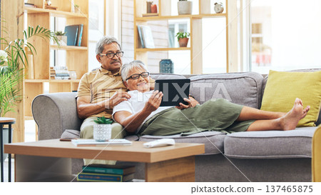 Relax, senior couple and a tablet for a movie, reading information or streaming a film on the sofa. Smile, house and an elderly man and woman with technology for a show, notification or an email Relax, senior couple and a tablet for a movie, reading information or streaming a film on the sofa. Smile, house and an elderly man and woman with technology for a show, notification or an email 137465875