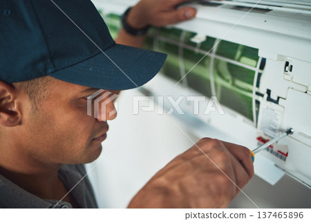 Face, hand and a man for aircon repair or maintenance in an office for circulation or central heating. Construction, tools or screwdriver with an engineer working on an air conditioning unit closeup Face, hand and a man for aircon repair or maintenance in an office for circulation or central heating. Construction, tools or screwdriver with an engineer working on an air conditioning unit closeup 137465896