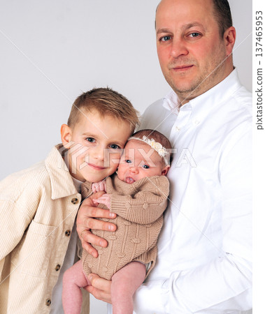 Father holding a baby while standing with his older son. Family portrait showing love, parenting and relationship between siblings. Concept of fatherhood, childhood and caring family environment. Father holding a baby while standing with his older son. Family portrait showing love, parenting and relationship between siblings. Concept of fatherhood, childhood and caring family environment. 137465953