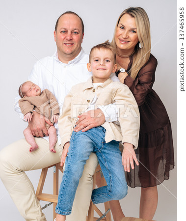 Happy parents sitting together with their children newborn baby and older boy. Warm family portrait showing love, parenting and emotional bonding. Concept of family happiness and childhood.  137465958