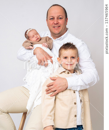 Father holding a newborn baby while standing with his young son. Warm family portrait showing fatherhood, parenting and emotional connection between siblings and parent. Concept of happy family and Father holding a newborn baby while standing with his young son. Warm family portrait showing fatherhood, parenting and emotional connection between siblings and parent. Concept of happy family and 137465964