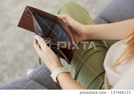 Close up young poor unemployed woman holding opened empty black leather wallet without cash 137466115