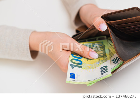 Woman placing 100 euro banknotes in brown wallet. Concept of budgeting, cash storage, income, payment, financial responsibility and money security in EU. Woman placing 100 euro banknotes in brown wallet. Concept of budgeting, cash storage, income, payment, financial responsibility and money security in EU. 137466275