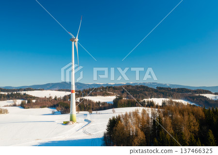 A wind turbine operates in an open field covered with snow during winter, symbolizing climate adaptation through renewable energy solutions. A wind turbine operates in an open field covered with snow during winter, symbolizing climate adaptation through renewable energy solutions. 137466325
