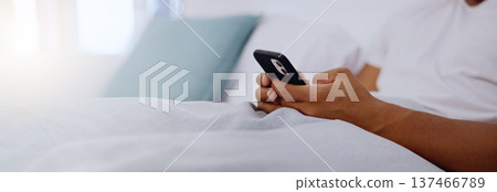 Typing, bed and hands of a man with a phone for social media, communication and chat. Contact, internet and guy scrolling on a mobile app for messages, reading emails or notification in the bedroom Typing, bed and hands of a man with a phone for social media, communication and chat. Contact, internet and guy scrolling on a mobile app for messages, reading emails or notification in the bedroom 137466789