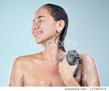 Clean, woman and shower with water, soap and sponge for healthy dermatology, skincare and blue background in studio. Person, smile and washing skin and body with foam bubbles in bathroom Clean, woman and shower with water, soap and sponge for healthy dermatology, skincare and blue background in studio. Person, smile and washing skin and body with foam bubbles in bathroom 137467074
