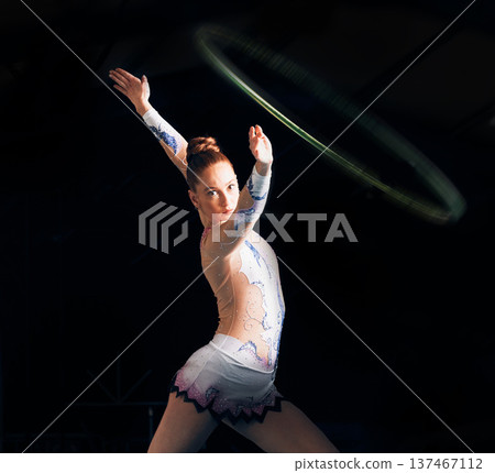 Fitness, energy with a gymnastics hoop and a woman in the gym for a performance showcase or practice. Dance, training and concert with a female athlete on a dark background for routine or recital 137467112