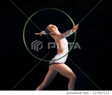 Dance, training with a gymnastics hoop and a woman in the gym for a performance showcase or practice. Fitness, energy and concert with a female athlete on a dark background for routine or recital Dance, training with a gymnastics hoop and a woman in the gym for a performance showcase or practice. Fitness, energy and concert with a female athlete on a dark background for routine or recital 137467113