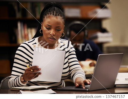 Student, woman and documents on laptop in library for study, research and planning in university. Young african person with paper and computer for reading or focus in English, education or philosophy 137467157