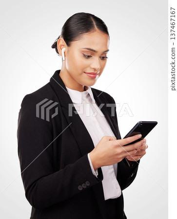 Communication, phone and earphones with a business woman in studio on a white background for networking. Contact, music and a happy young employee reading or typing a text message on her mobile 137467167