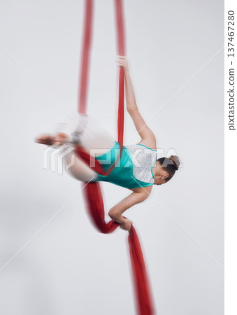 Aerial silk, acrobat and a woman in air for gymnastics performance, sports and balance. Behind athlete person or gymnast hanging on red fabric and white background with space, art and creativity Aerial silk, acrobat and a woman in air for gymnastics performance, sports and balance. Behind athlete person or gymnast hanging on red fabric and white background with space, art and creativity 137467280