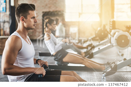 Training, man and rowing machine in gym for group class, fitness workout and cardio exercise. Strong bodybuilder, healthy athlete and challenge to row on sports equipment for energy, muscle and power 137467412
