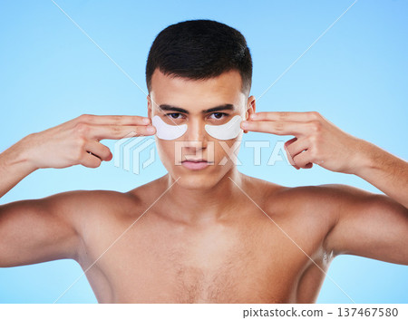 Man, beauty and face with eye patch for skincare, grooming and clean with hygiene isolated on blue background. Skin treatment, cosmetics product and wellness, portrait and dermatology in a studio Man, beauty and face with eye patch for skincare, grooming and clean with hygiene isolated on blue background. Skin treatment, cosmetics product and wellness, portrait and dermatology in a studio 137467580