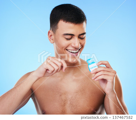 Dental floss, man and teeth cleaning for healthcare, wellness and morning care in studio. Blue background, male model and happy from mouth hygiene with smile from healthy product for tooth protection Dental floss, man and teeth cleaning for healthcare, wellness and morning care in studio. Blue background, male model and happy from mouth hygiene with smile from healthy product for tooth protection 137467582