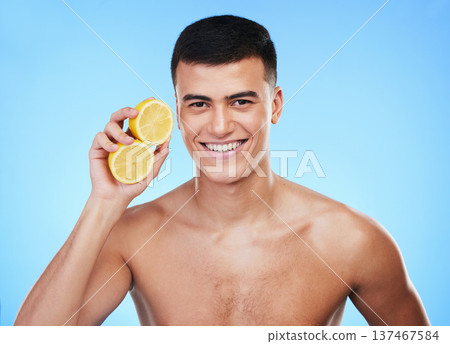 Beauty, health and portrait of man and lemon in studio for health, detox and natural cosmetics. Vitamin c, nutrition and skincare with person and fruit on blue background for self care, spa and glow 137467584
