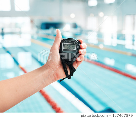 Person, hand and stopwatch by pool in swimming, race or sports training in fitness, exercise or workout. Closeup of swim coach holding timer for monitoring performance, speed or setting challenge Person, hand and stopwatch by pool in swimming, race or sports training in fitness, exercise or workout. Closeup of swim coach holding timer for monitoring performance, speed or setting challenge 137467879