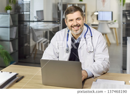 Smiling doctor at laptop in clinic office, telehealth consultation concept 137468190