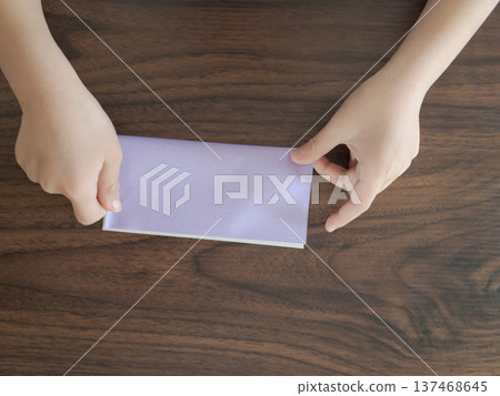 孩子的小手正在整理淺紫色摺紙的邊緣。 137468645